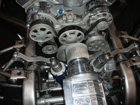 1998 Ford Crown Victoria - front of a polished V8 engine shows aluminum serpentine pulleys, a supercharger snout and chrome suspension components.