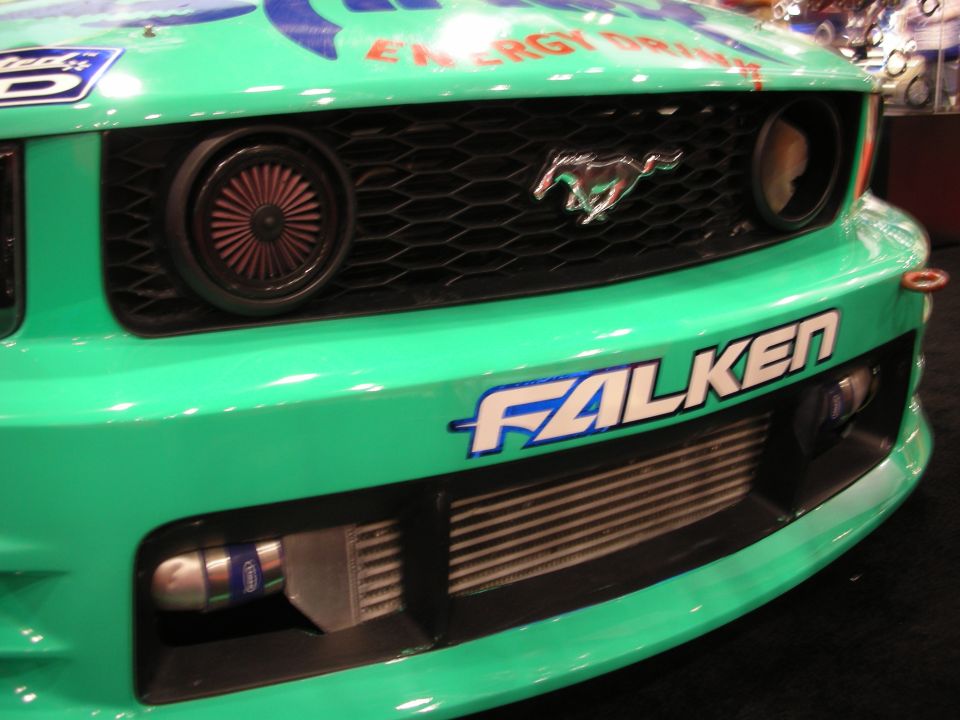 Close-up of teal Ford Mustang front grille with pony emblem and Falken decal