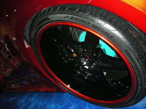 1998 Ford Crown Victoria - Close-up of a black multi-spoke wheel with a red lip wrapped in a Pirelli P Zero Nero tire on a red car.