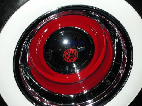 1998 Ford Crown Victoria - Close-up of a chrome and red hubcap on a whitewall tire bearing a small SEMA logo at its center.