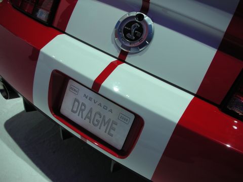 1998 Ford Crown Victoria - Rear deck of a red car with a white stripe and round fuel cap, displaying a Nevada SEMA vanity plate reading DRAGME.