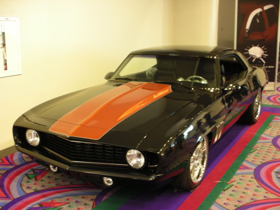 Black muscle coupe with orange center stripe on patterned carpet indoors