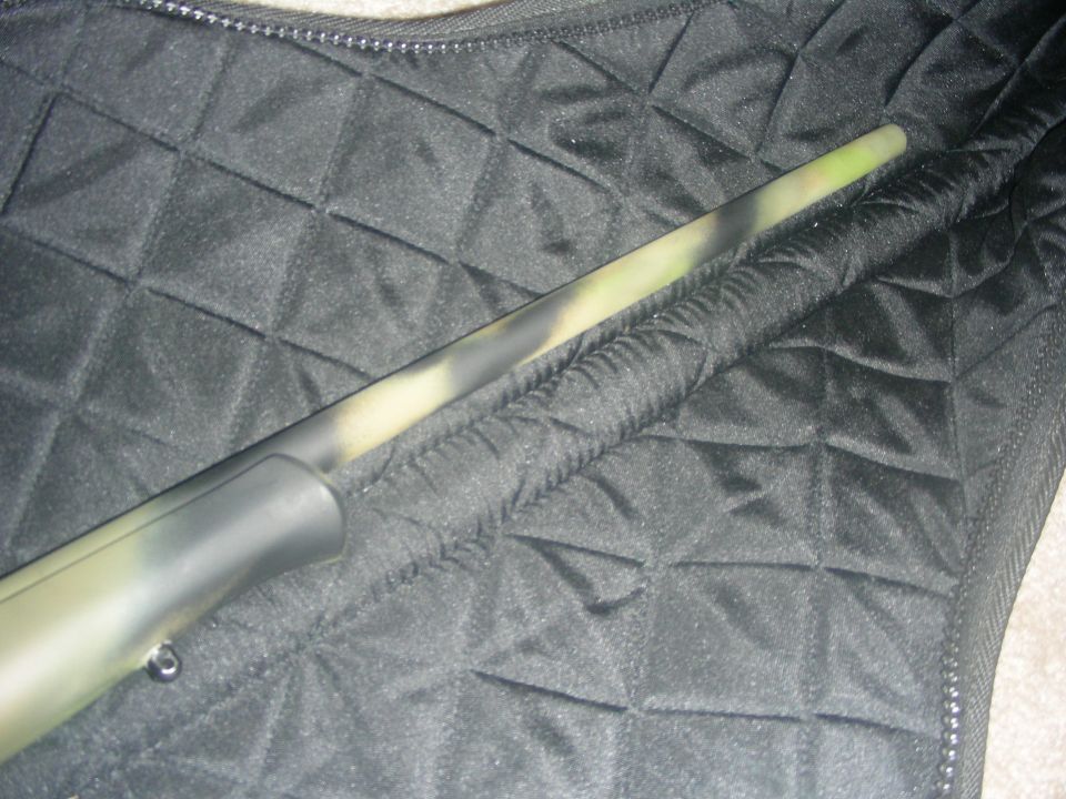 Camouflage rifle barrel resting on a quilted black fabric case