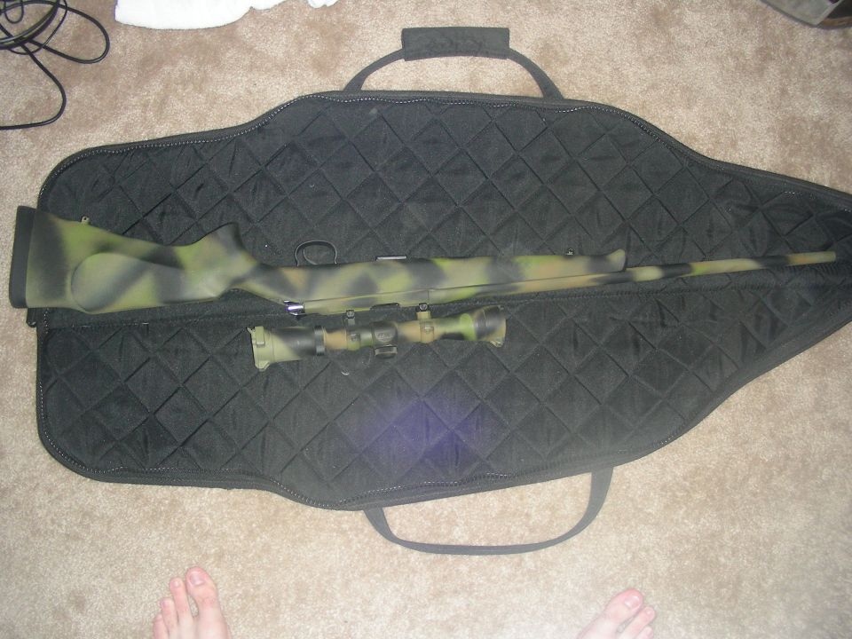 Rifle with camouflage paint and scope inside a black quilted gun bag