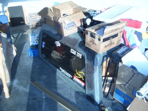 1988 Ford Bronco - A truck bed is overloaded with various boxes, including Bud Light and Amber Bock, with a 'TEXAS TOYS' sticker visible on the rear window.