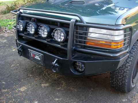 1993 Ford Bronco - Front view of a green SUV a heavy-duty brush guard with KC lights and an aftermarket bumper.