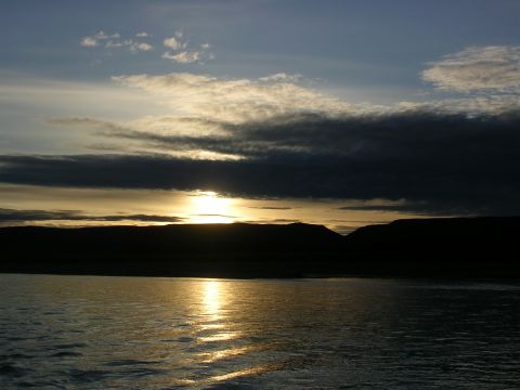 1982 Chevrolet C/K Pickup - The sun sets behind silhouetted hills, casting a golden reflection on the water below.