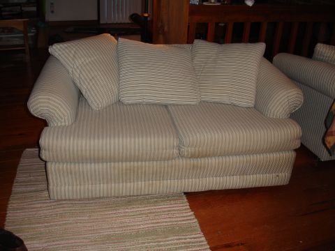 1996 Ford Bronco - A sofa with striped upholstery and cushions sits on a wooden floor next to a rug.