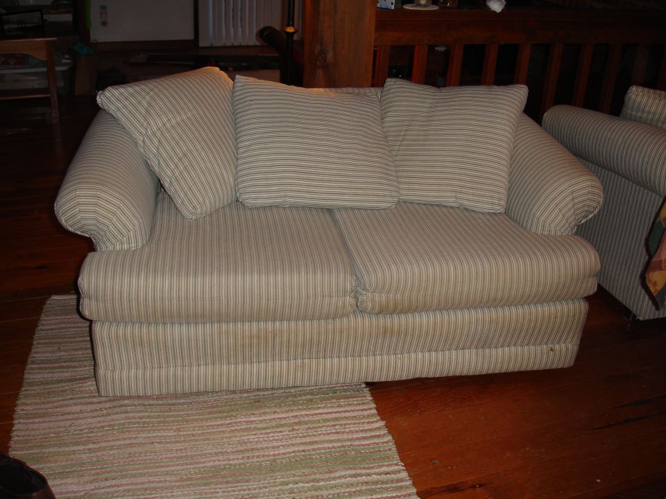 Striped sofa with three cushions on a wooden floor with a rug