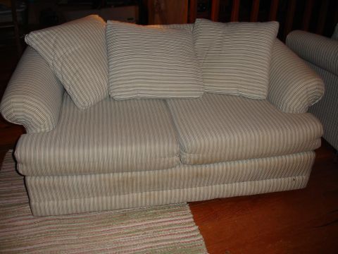 1996 Ford Bronco - A striped sofa with cushions sits on a wooden floor next to a rug.