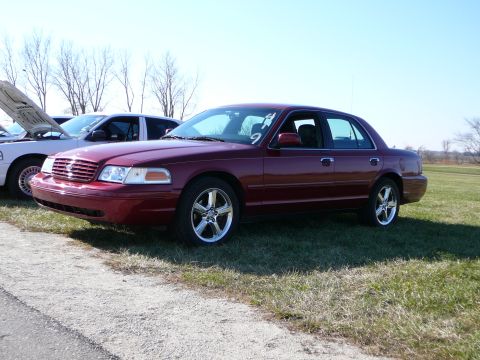 1997 Mercury Grand Marquis - A maroon sedan is parked on grass next to a white vehicle, with a number 9 visible on the windshield.