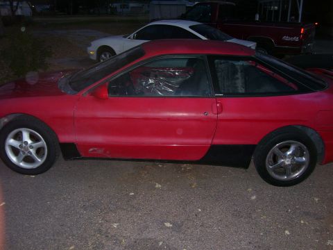 1993 Mazda MX-6 - Side view of a red 1993 Mazda MX-6 coupe parked outdoors with other vehicles.