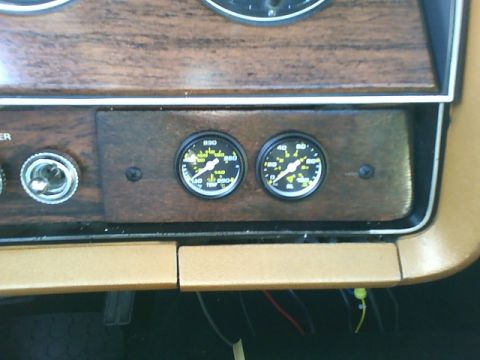 1979 Ford Ranchero - Close-up of aftermarket gauges installed in a vehicle's dashboard, woodgrain trim.