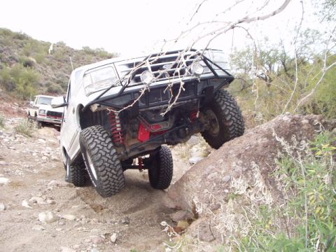 1993 Ford Bronco - A modified white Ford Bronco navigates a rocky trail, with another vehicle visible in the background.