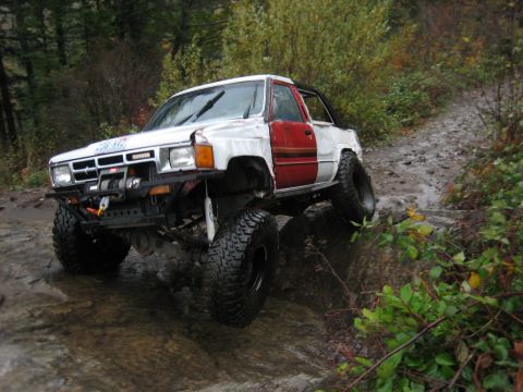 1990 Ford Bronco - This heavily modified Toyota pickup truck navigates a challenging off-road course with large tires and a lifted suspension.