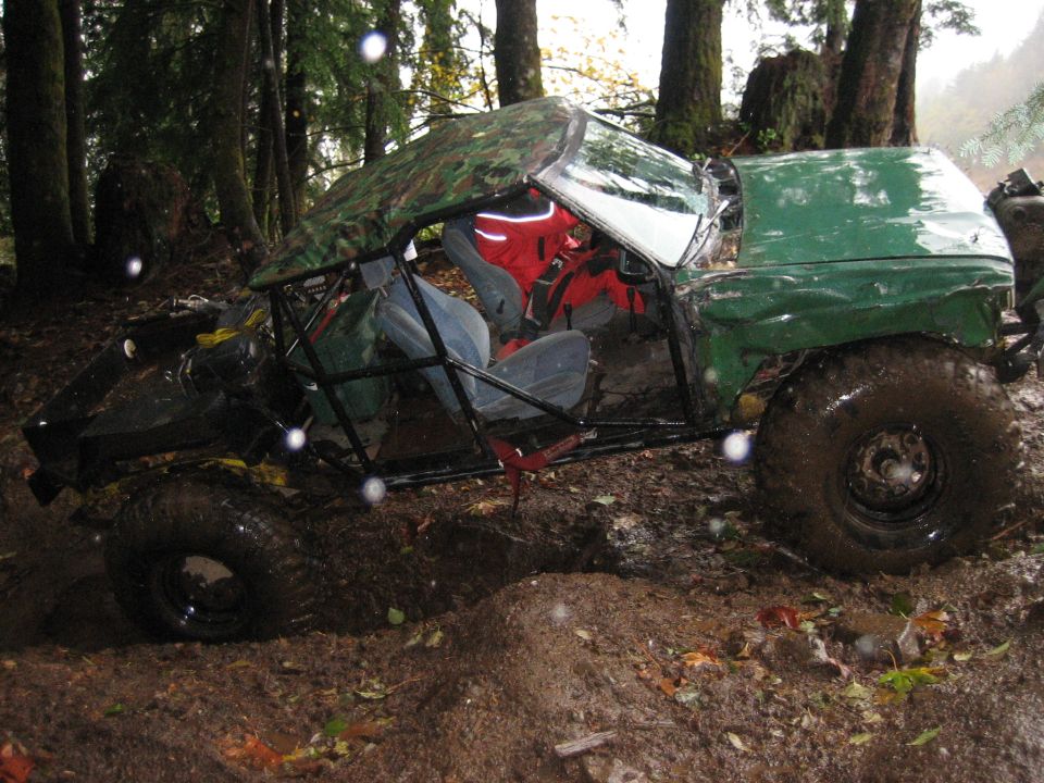 Green off-road vehicle with roll cage stuck in mud