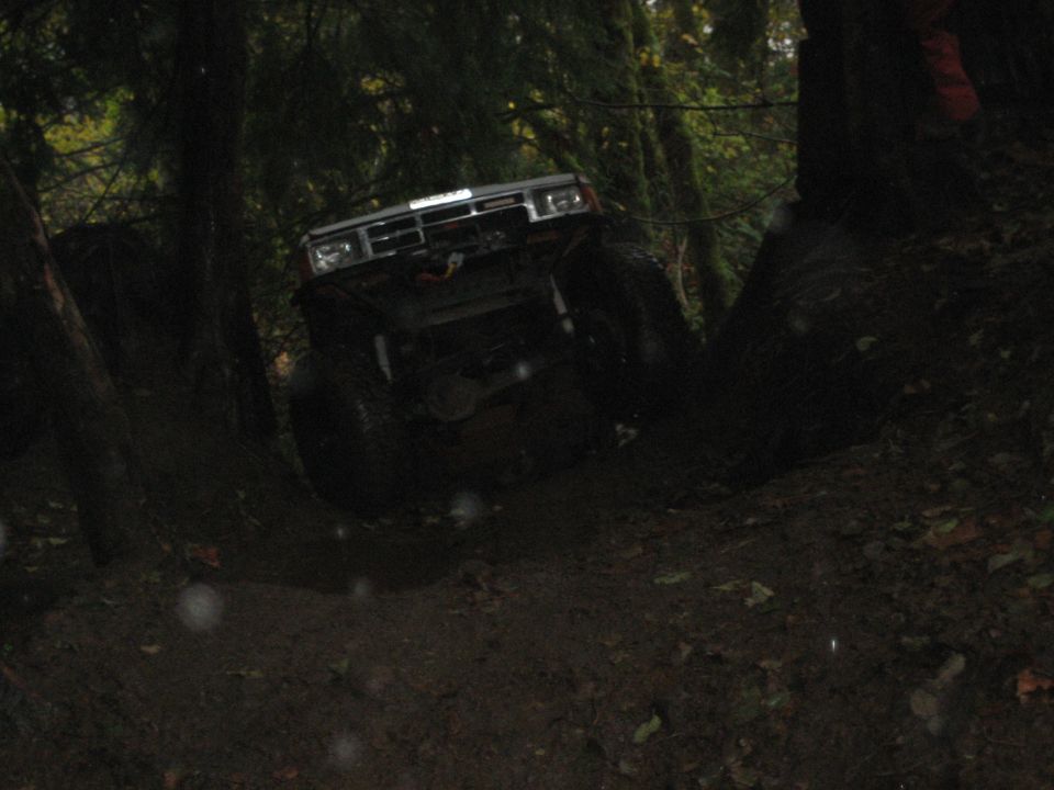 1990 Ford Bronco climbing a muddy hill in a forest
