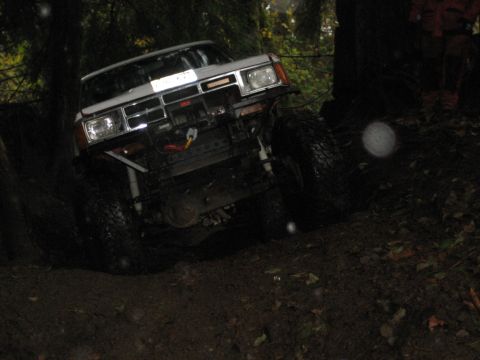 1990 Ford Bronco - A modified off-road vehicle navigates a wet, wooded path.