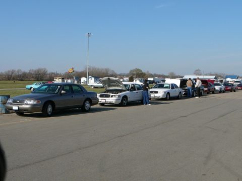 1997 Mercury Grand Marquis - Multiple 1997 Mercury Grand Marquis sedans are lined up on an asphalt surface, with some hoods open.