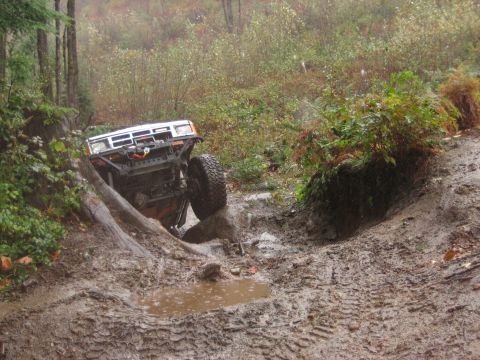 1990 Ford Bronco - This off-road vehicle appears to be stuck in a challenging muddy terrain, tilted precariously.