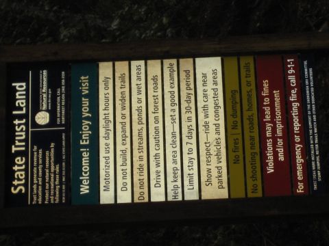 1990 Ford Bronco - A sign lists rules for State Trust Land, covering visitor conduct, fire restrictions, and emergency procedures.