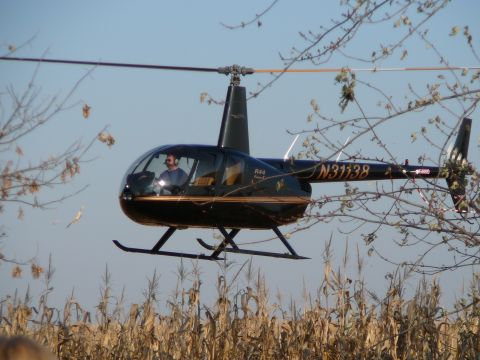 1997 Mercury Grand Marquis - A Robinson R44 helicopter with registration N31138 flies low over a dry cornfield.