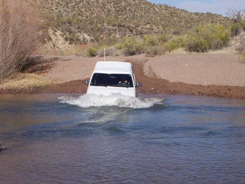1993 Ford Bronco - White 1993 Ford Bronco fords a shallow river in a desert environment.