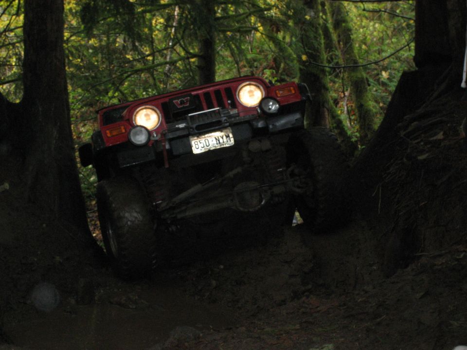 Red Jeep Wrangler climbing muddy terrain