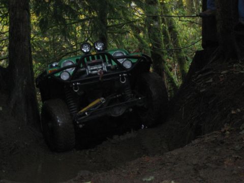 1990 Ford Bronco - A modified Jeep navigates a challenging off-road trail through a dense forest.