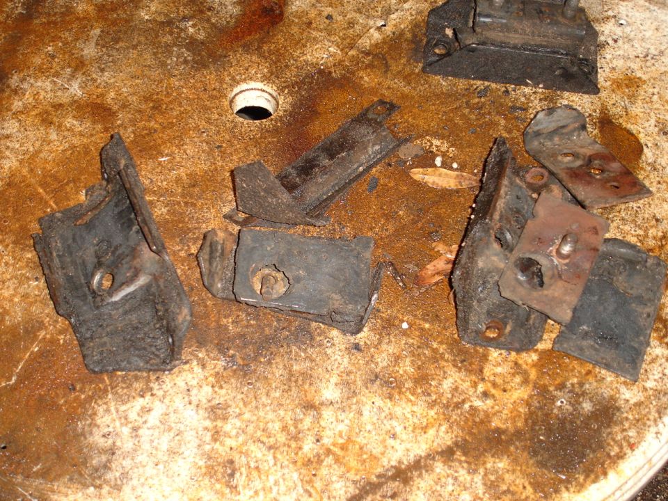 Pile of rusty, broken metal brackets and rubber mounts on a dirty surface