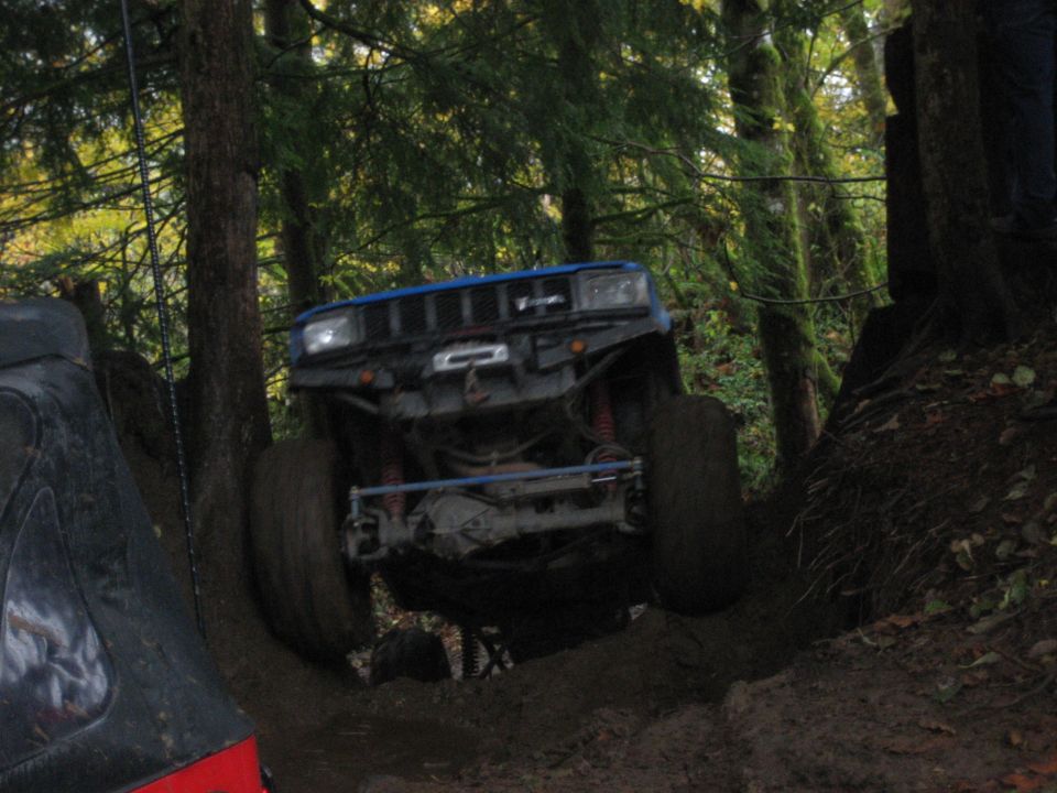 Blue off-road SUV climbing a muddy hill, front view