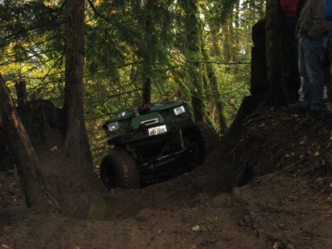 1990 Ford Bronco - A green 1990 Ford Bronco navigates a challenging muddy off-road course.