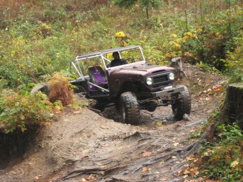 1990 Ford Bronco - A customized Toyota Land Cruiser FJ40 navigates a challenging off-road course with a roll cage and custom seats.
