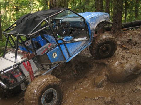 1990 Ford Bronco - Custom off-road vehicle navigates a muddy trail through a forest.