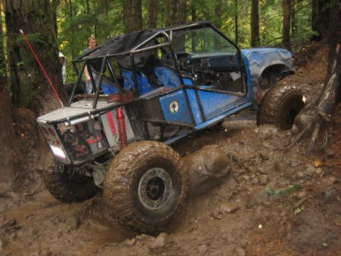 1990 Ford Bronco - Custom buggy navigating a difficult muddy trail in a forest setting.