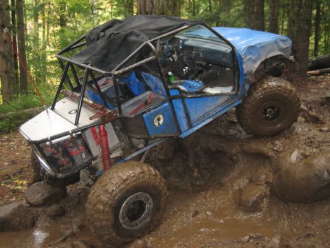 1990 Ford Bronco - This heavily modified buggy navigates a challenging muddy terrain with large off-road tires.