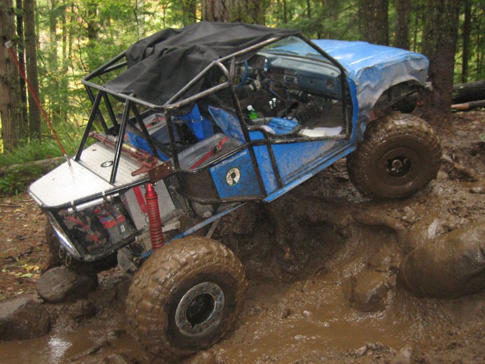 Blue buggy with roll cage going over mud and rocks