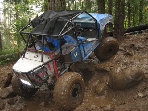 1990 Ford Bronco - This heavily modified buggy navigates a challenging muddy terrain with large off-road tires and a protective roll cage.