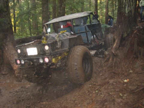 1990 Ford Bronco - This heavily modified off-road vehicle is stuck deep in the mud on a forest trail.