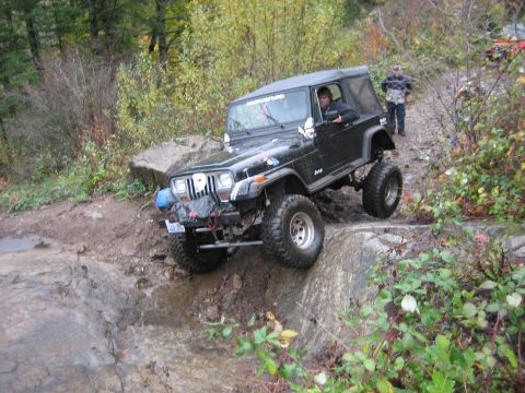 1990 Ford Bronco - Off-roading in a modified Jeep Wrangler on a challenging rocky path.