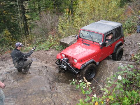 1990 Ford Bronco - Off-roading in a red Jeep Wrangler on a challenging rocky trail.