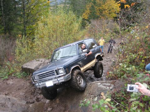 1990 Ford Bronco - Ford Bronco tackling a challenging off-road course with onlookers present.