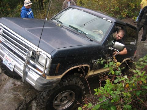 1990 Ford Bronco - 1990 Ford Bronco tackling a rocky trail with a driver behind the wheel.