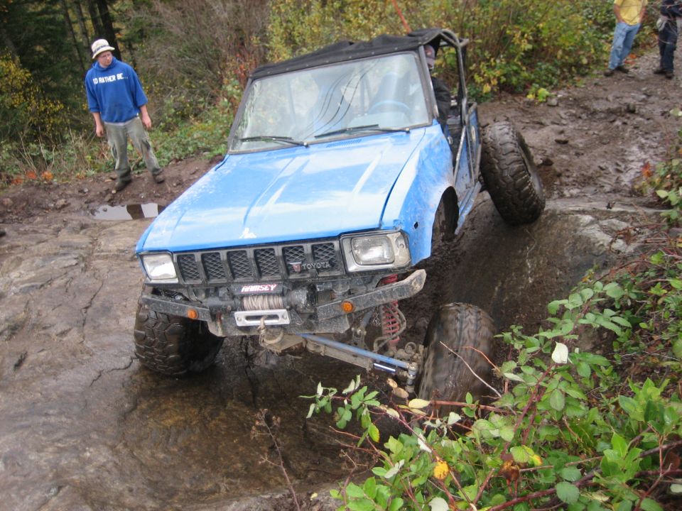 Blue off-road vehicle with a winch on the front bumper, stuck on a rocky trail