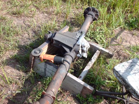 1982 Ford F-100 - A rear axle assembly is shown with a grinder tool attached, resting on wooden supports in a grassy area.