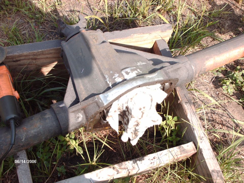 Axle housing on boards with freshly ground bare metal and a rag stuffed in the diff opening