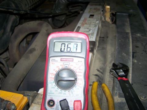 1995 Ford Bronco - Multimeter reading 0.67 in an engine bay with tools present.
