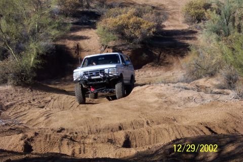 1993 Ford Bronco - A white 1993 Ford Bronco navigates an off-road dirt path.