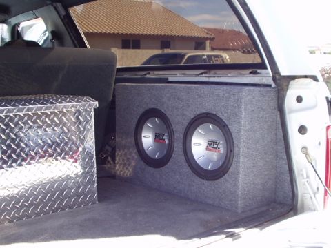 1993 Ford Bronco - The interior of a white SUV shows a custom subwoofer box and a diamond plate toolbox in the cargo area.