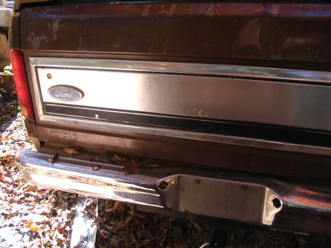 1984 Ford Bronco - Rear view of a brown Ford truck, showing the tailgate panel and chrome bumper.